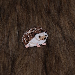 May include: A white ceramic mug with a black handle and the text "But First, Coffee" in a black, handwritten-style font. The mug is on a white surface.