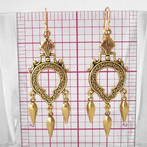 Peut inclure: Une paire de boucles d'oreilles pendantes dor&eacute;es et orn&eacute;es. Chaque boucle d'oreille pr&eacute;sente un dessus d&eacute;coratif avec un motif circulaire et trois pendentifs en forme de goutte. Les boucles d'oreilles mesurent environ 7.6 cm de long.