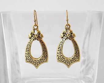May include: A pair of gold filigree dangle earrings with a teardrop shape and intricate floral designs.