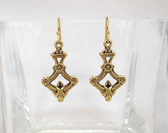 May include: A pair of gold-tone dangle earrings with a geometric design. The earrings have a diamond shape with intricate details.