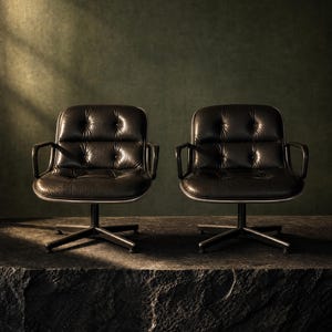 Peut inclure: Deux fauteuils en cuir noir avec dossiers et assises capitonnés. Chaque fauteuil présente des accoudoirs noirs incurvés et une base centrale sur pied avec quatre pieds rayonnants, offrant une assise stable et profilée.