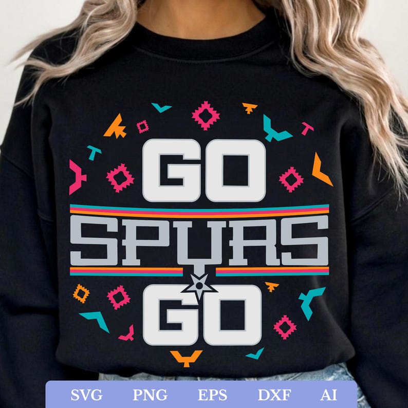 Op de afbeelding: Zwart sweatshirt met de witte tekst "GO SPURS GO", een ster en geometrische vormen in teal, oranje en roze. Het ontwerp bevat de kleuren en het logo van het team.