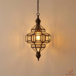May include: An ornate, hanging pendant light with a geometric design. The light fixture features a dark metal frame and clear glass panels. The light is suspended from a chain and emits a warm, inviting glow. A decorative element for home decor.