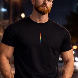 May include: Black crew neck t-shirt with a vertical rainbow stripe design. The shirt is made of a soft material and is suitable for casual wear. The t-shirt is a simple design with a colorful accent.