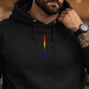 May include: Black hoodie with a vertical rainbow stripe design. The hoodie has a drawstring hood and a front pocket. The rainbow stripe is a vibrant display of colors, including red, orange, yellow, green, blue, and purple.