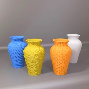 May include: A set of three ceramic mugs with a speckled, matte finish. The mugs are in shades of cream, light grey, and dark grey. Each mug has a simple, minimalist design and a rounded handle. The mugs are stacked on top of each other.