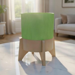 May include: A contemporary planter featuring a light green, vertically ribbed cylindrical top and a natural wood-toned base. The planter is supported by three angled wooden legs, creating a stylish, minimalist design. Suitable for indoor plants.