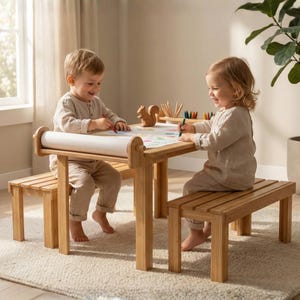 Könnte beinhalten: Ein helles Holztischchen für Kinder mit angebrachten Bänken. Zwei Kinder sitzen an dem Tisch und zeichnen mit Buntstiften auf einer Papierrolle. Eine Holzfigur eines Eichhörnchens und ein Tablett mit Buntstiften befinden sich auf dem Tisch.