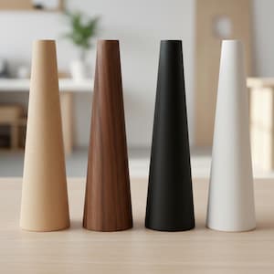 May include: Four cone-shaped objects in a row. From left to right, they are light wood, dark wood, black, and white. The objects are on a light-coloured wooden surface.