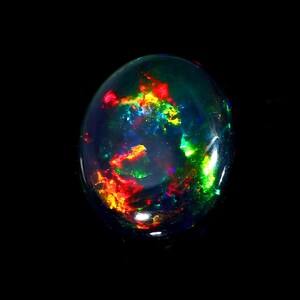 May include: A polished, oval-shaped black opal gemstone. The opal displays a vibrant play-of-color, with flashes of red, yellow, green, and blue. The gemstone is set against a black background, highlighting its iridescent qualities.