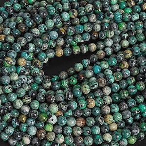 May include: A strand of green and brown gemstone beads. The beads are round and have a speckled pattern. The beads are strung on a green thread.