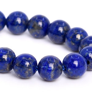 Puede incluir: Una hebra de cuentas redondas y lisas de lapislázuli azul oscuro con motas de pirita dorada. Las cuentas están enhebradas en un cordón elástico transparente.