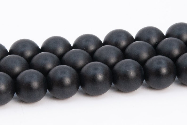 May include: A strand of black round beads, made of polished onyx, arranged in a row.