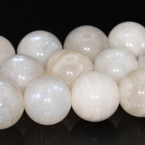 May include: A strand of white moonstone beads, each bead is a smooth sphere with a subtle iridescent sheen.