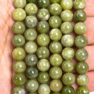 May include: A strand of green jade beads, each bead is round and smooth with a light green colour and white marbling.
