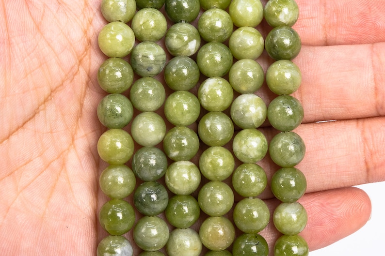 May include: A strand of green jade beads, each bead is round and smooth with a light green colour and white marbling.