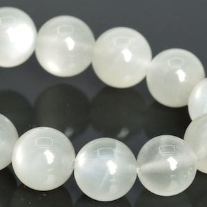 May include: A white gemstone bracelet with round beads. The beads are smooth and have a subtle shimmer.