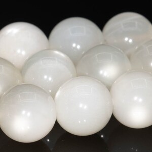 May include: A strand of white moonstone beads. The beads are round and smooth, with a subtle iridescent sheen.