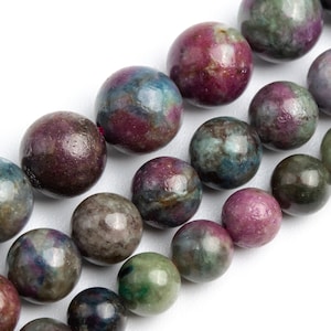 May include: Strands of round gemstone beads in shades of burgundy, green, and gray. The beads have a mottled appearance and are arranged in parallel rows against a white background. These beads are suitable for jewelry making.