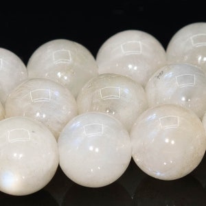 May include: A strand of white moonstone beads, each bead is a smooth sphere with a subtle iridescent sheen.