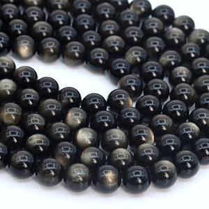 May include: A strand of black obsidian beads with gold flecks. The beads are round and smooth, and they are strung together on a clear thread.