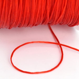 May include: A spool of bright red waxed cord, with a length of cord extending from the spool.