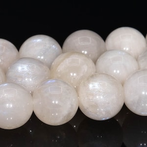 May include: A strand of white moonstone beads, each bead is a smooth sphere with a subtle iridescent sheen.