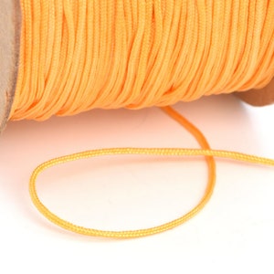 May include: A spool of bright yellow waxed cord, with a length of cord extending from the spool.