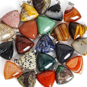 May include: A collection of triangular gemstone pendants featuring various colors and patterns, including pink, yellow, black, orange, green, blue, and spotted textures. Each polished stone is fitted with a silver-toned metal bail for hanging.