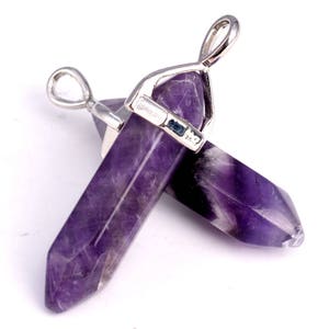 May include: Two amethyst crystal point pendants with silver-toned metal bails. The crystals are a deep purple color and have a pointed shape.