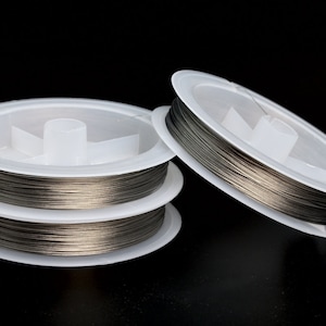 May include: Two spools of silver-colored wire on white plastic spools. The spools are stacked on top of each other.