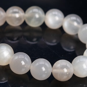 May include: A white moonstone bracelet with round beads. The bracelet is made of natural stones and has a polished finish.