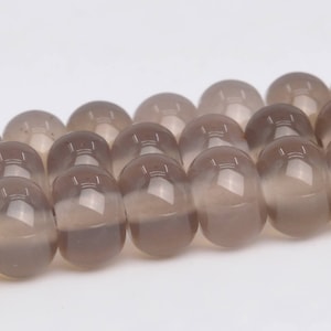 May include: A strand of gray agate beads, each bead is round and smooth. The beads are strung together on a clear thread.