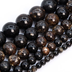 May include: A strand of black and brown gemstone beads. The beads are round and have a speckled appearance.