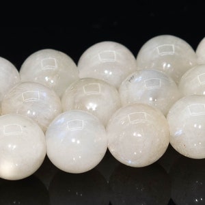 May include: A strand of white moonstone beads, each bead is round and smooth, with a subtle shimmer.