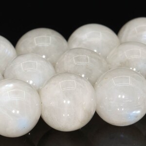 May include: A strand of white moonstone beads. The beads are round and smooth, with a subtle iridescent sheen.