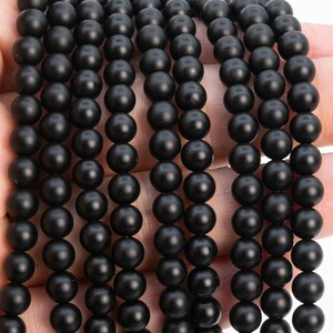 May include: A strand of black matte round beads. The beads are uniform in size and have a smooth, polished finish.