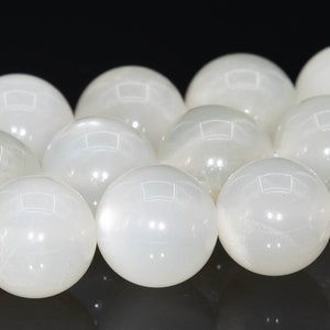May include: A strand of white moonstone beads, each bead is round and smooth, with a subtle iridescent sheen.