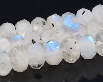 May include: A strand of white moonstone beads with iridescent blue and black flecks. The beads are faceted and have a smooth, polished finish.