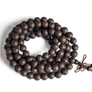 May include: A dark brown wooden beaded necklace with a tassel. The beads are round and smooth, and the necklace is strung on a brown cord.