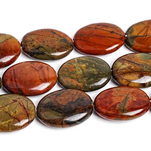May include: A close-up of a strand of polished, oval-shaped beads. The beads are a mix of earthy tones, including reddish-brown, olive green, and dark brown, with intricate veining patterns. The beads are strung together, ready for jewelry making.