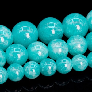 May include: A strand of turquoise blue gemstone beads with a white marbled pattern. The beads are round and smooth, and they are arranged in a line.