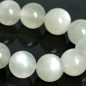 May include: A strand of white moonstone beads, each bead is round and smooth with a subtle iridescent sheen.