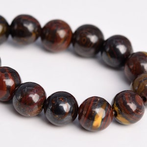 May include: A strand of round, dark brown, red, and gold beads with a metallic sheen. The beads are made of hematite.