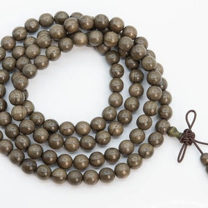 May include: A brown wooden beaded necklace with a knotted tassel. The beads are round and have a smooth, polished finish.