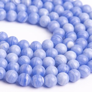 Puede incluir: Una hebra de cuentas de &aacute;gata azul claro con remolinos blancos. Las cuentas son redondas y lisas.
