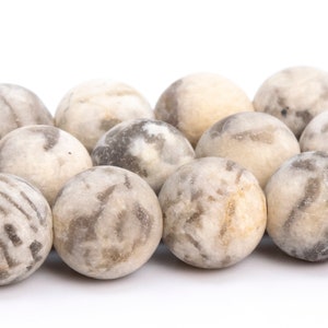 May include: A strand of round, white and gray agate beads. The beads have a marbled pattern and are smooth and polished.