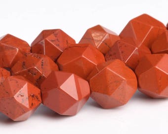 May include: A strand of red gemstone beads, each bead is faceted and shaped like a star. The beads are arranged in a curved line, with the points of the stars facing outwards.