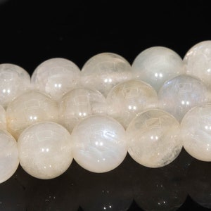 May include: A strand of white moonstone beads. The beads are round and smooth, with a slight iridescent sheen.