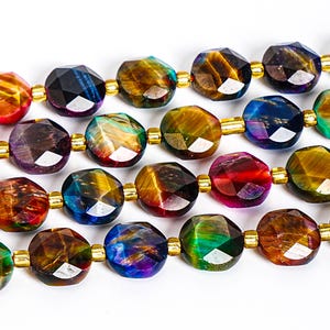 Könnte beinhalten: Nahaufnahme einer Kette aus facettierten Edelsteinperlen. Die Perlen sind eine Mischung aus Farben, darunter Gold, Blau, Lila und Rot. Jede Perle wird durch einen kleinen goldfarbenen Abstandhalter getrennt. Die Perlen sind aufgereiht und bilden eine Halskette oder ein Armband.